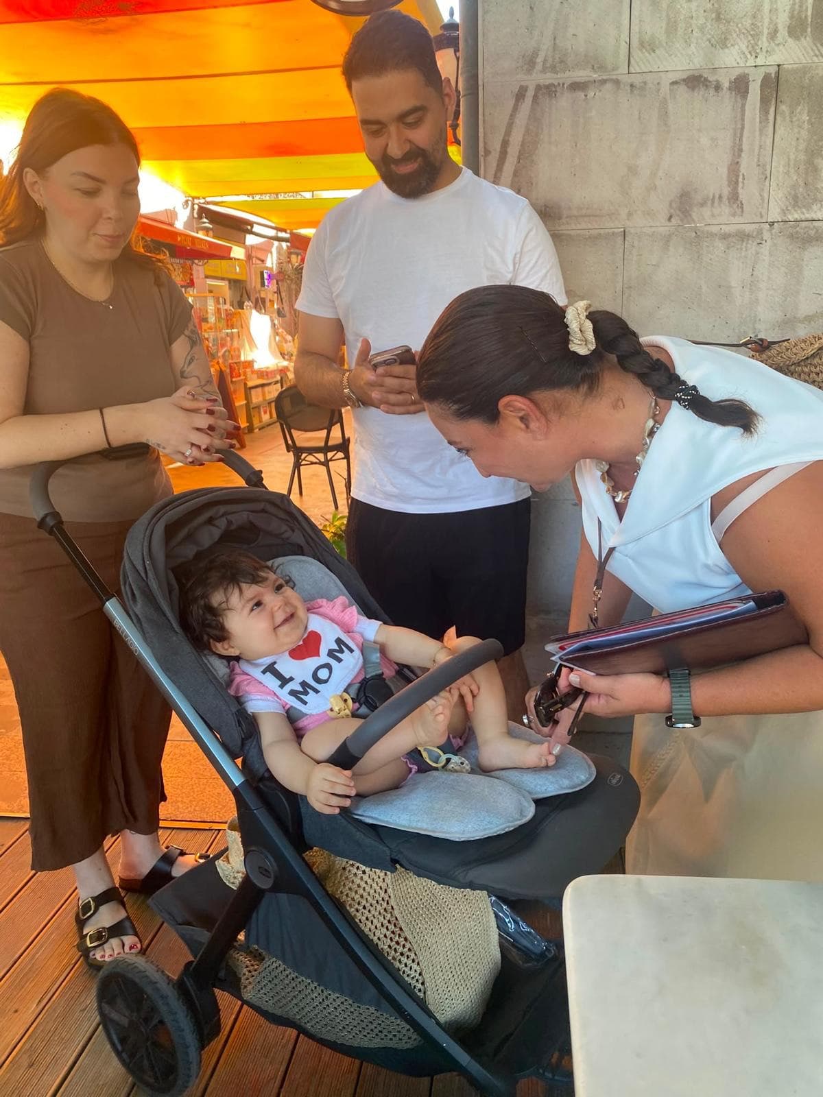 Licensed guide Fulya Tamer greeting a baby in a stroller while the parents look on, at Kuşadası port before a private family Ephesus tour, 26 August 2026