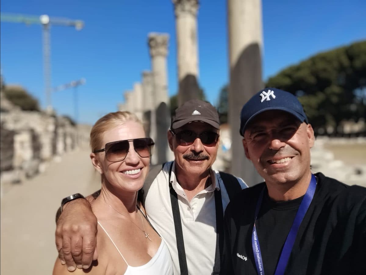 Russian-speaking licensed guide Cihan Yaşkaya with two Holland America Oosterdam guests, Cihan on the right taking the selfie, among the standing columns of Ephesus, on a private Ephesus, House of the Virgin Mary and Temple of Artemis tour in Russian from Kuşadası cruise port, 9 October 2026