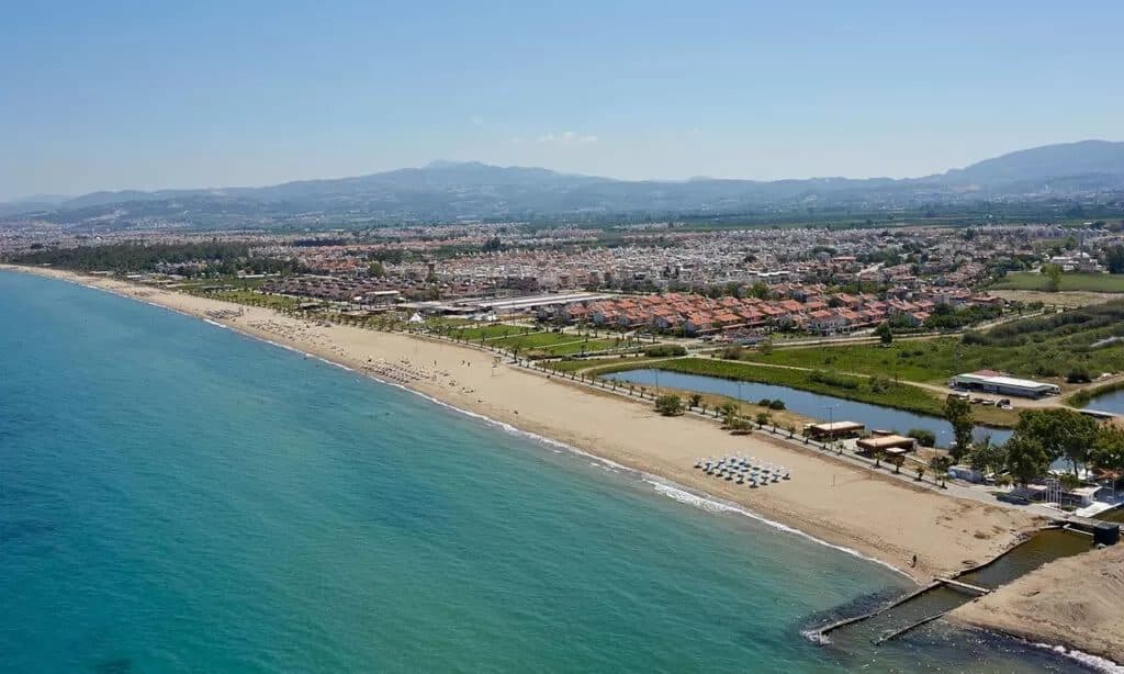 Aerial view of Long Beach (Uzun Plaj) in Kuşadası with a long sandy shore, beach clubs and the Aydın mountains in the background, ten minutes by taxi from the cruise port