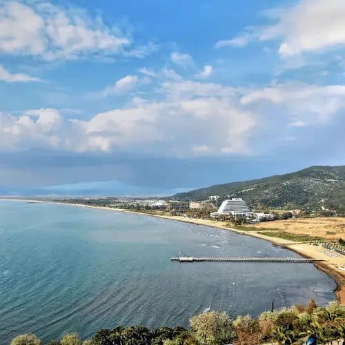 Wide sandy Pamucak Beach near Ephesus with the Pamucak pyramid-shaped resort on the headland, twenty-five minutes by taxi from the Kuşadası cruise port