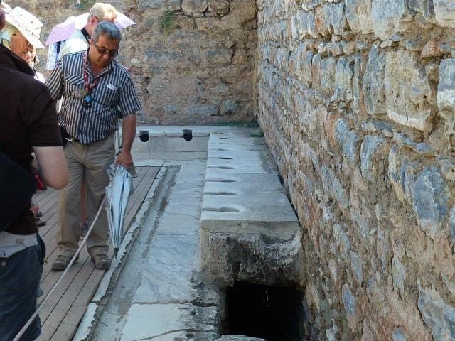 Guide showing guests the Roman public latrines of Ephesus