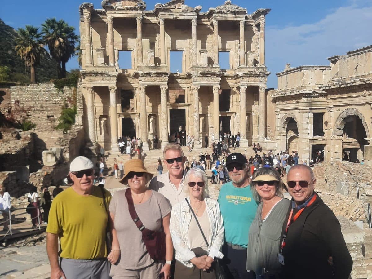 Licensed French- and English-speaking guide Eli Halegua, on the right in a dark jacket, with six Canadian guests from Celebrity Ascent in front of the Library of Celsus, on a private Ephesus and Temple of Artemis tour from Kuşadası cruise port, 22 October 2026