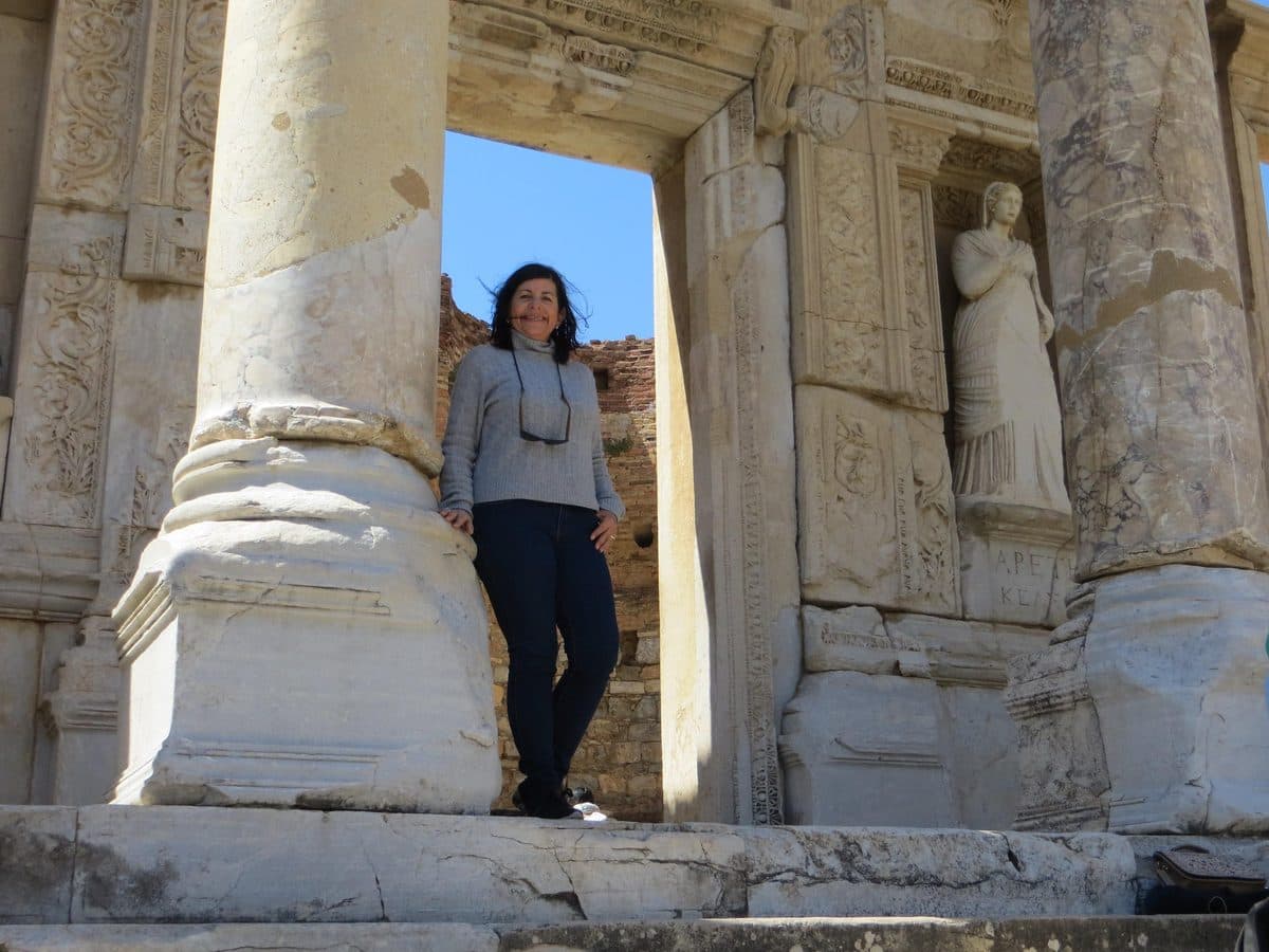 A guest standing between the columns of the Library of Celsus beside the statue of Arete