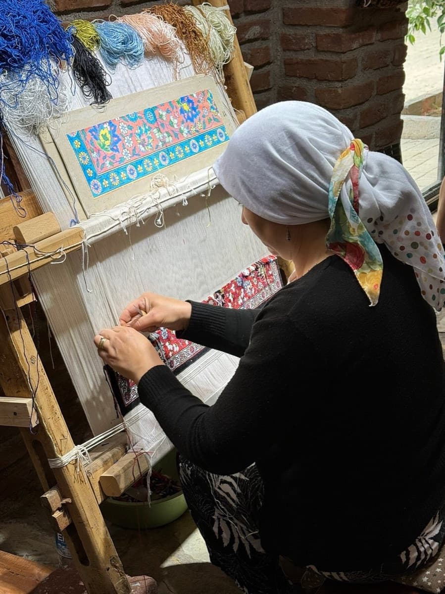 A weaver at the loom with naturally dyed silk thread at a family carpet workshop near Ephesus