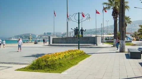 Palm-lined Atatürk Boulevard promenade curving along the Kuşadası seafront toward the cruise port
