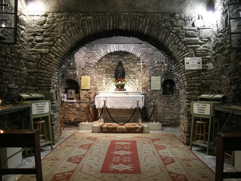 Chapel altar inside the House of the Virgin Mary with white lace cloth, flowers and the statue of Mary in the brick niche