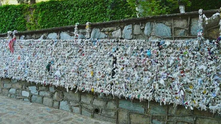The wish wall at the House of the Virgin Mary, thousands of tied ribbons and paper petitions below an ivy-covered wall