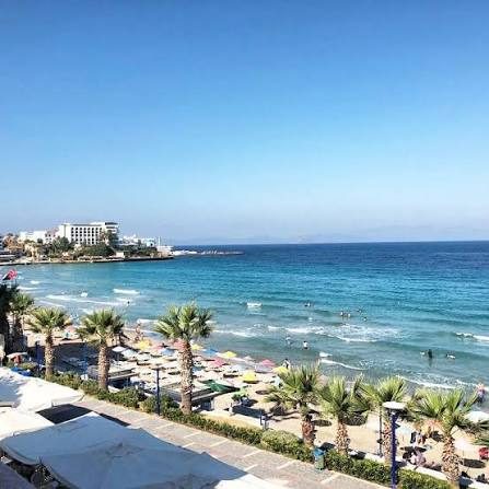 Ladies Beach, Kadınlar Plajı, in Kuşadası with rows of sun umbrellas, turquoise water and seafront hotels behind the sand